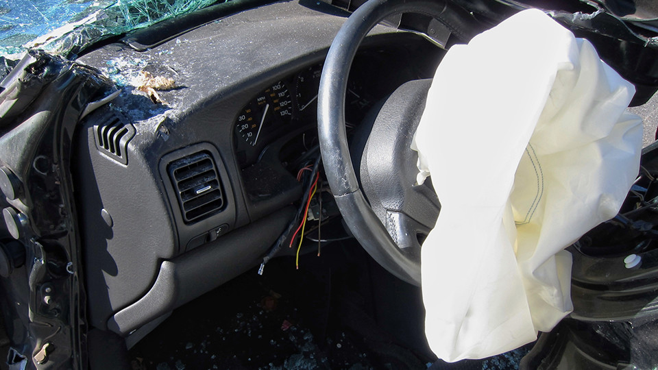 deployed airbags inside a car with a black dashboard