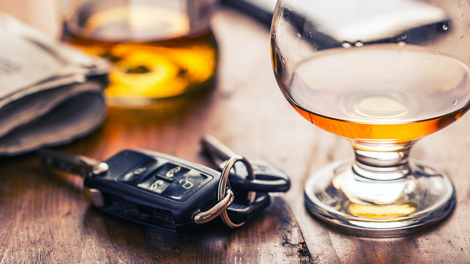 a table with car keys and a glass with alcohol