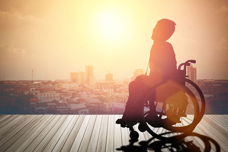 Person in a wheel chair on a deck overlooking the sunset