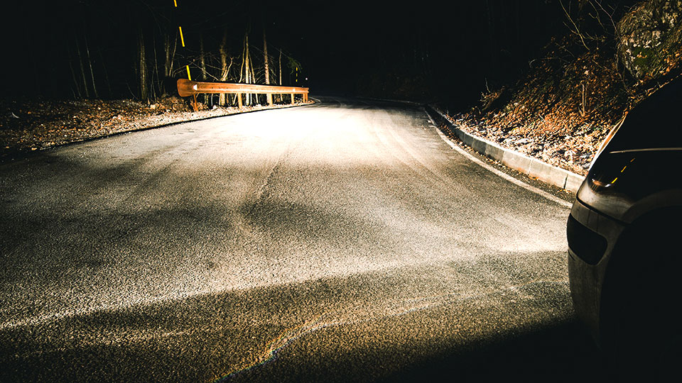 a curve in a dark road only lit by headlights