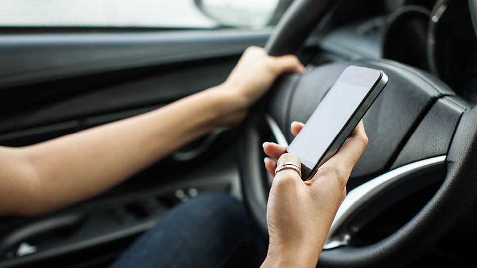 woman texting on a mobile device while driving