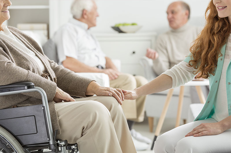 nurse holding the hand of a person in a wheelchair